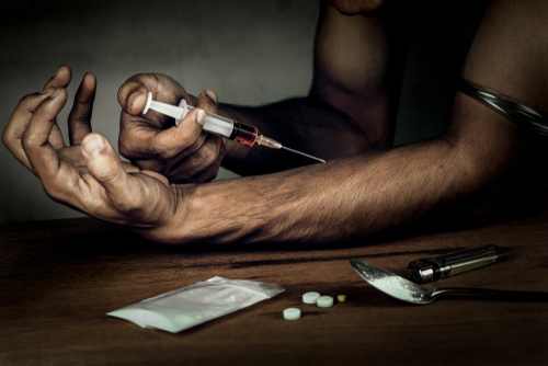 man using heroin needle