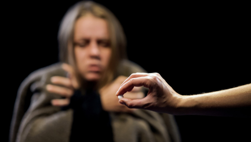 person offering pill to woman in background