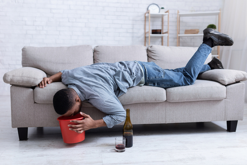 man laying on couch throwing up