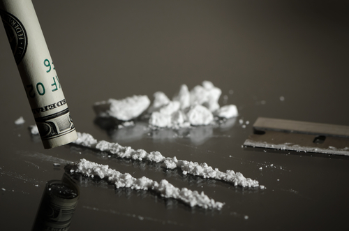 rolled up dollar bill being used to snort cocaine